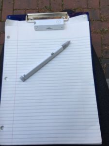 On top of a clipboard an Equil transmitter attached to paper with an Equil smartpen lying across the paper.